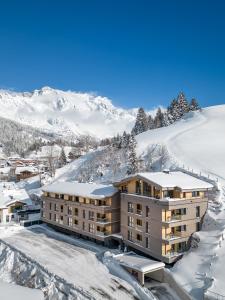 um edifício de apartamentos na neve com montanhas ao fundo em Wildbach Lodge Dienten em Dienten am Hochkönig