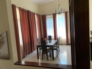 a dining room with a table and some windows at Elegant 3 Bedroom Space Available in Accra