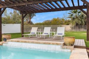a wooden pergola with chairs and a table next to a pool at Farrier by AvantStay Spectacular 7BR Mediterranean-style Estate w Pool in Scottsdale