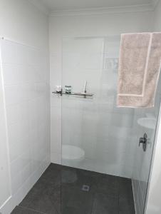 a white bathroom with a shower and a sink at The Heart of Glenelg in Glenelg
