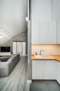 eine Küche mit weißen Schränken und einem Sofa in einem Zimmer in der Unterkunft Modern 2-bedroom Apartment in Old Town/URBAN RENT in Kaunas