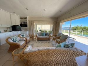 a living room with wicker furniture and a balcony at Villa Azure - Sea Views, Pool - 70m onto Robberg 5 Beach in Plettenberg Bay
