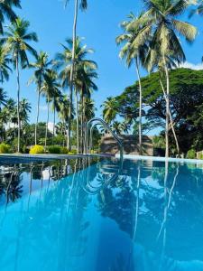 a swimming pool with palm trees in the background at Deduru Cabana Nature Resort in Kurunegala