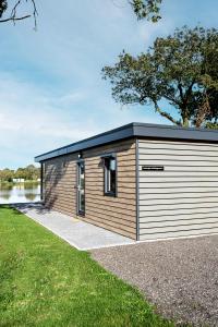 un pequeño edificio de madera con techo negro en Friesensee Camping und Ferienpark, en Wittmund