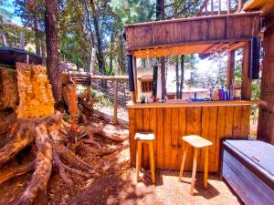 un bar in legno nel bosco con due sgabelli di OCTLI CABAÑA Y PULQUERIA a San Cristóbal de Las Casas