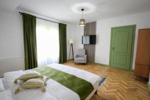 a bedroom with a bed with a green door and a chair at Chalet Bora in Vişeu de Jos
