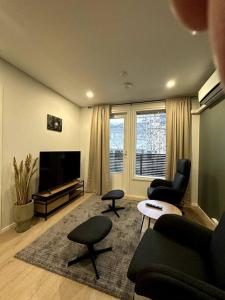 ein Wohnzimmer mit einem Sofa, Stühlen und einem TV in der Unterkunft Kotimaailma Apartments#5 - Boheemi kaksio keskustassa in Seinäjoki