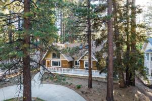 a house with a porch in the woods at Hartwood by AvantStay Cozy Big Bear Abode w Spacious Deck Stone Fireplace in Big Bear Lake