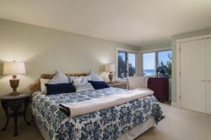 a bedroom with a bed with a blue and white bedspread at Chapman Cove by AvantStay Gorgeous Beach Bungalow w Sauna in Cannon Beach