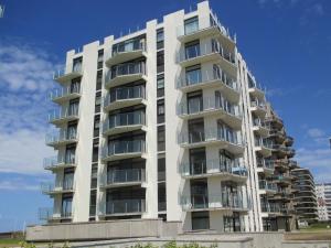 a tall white apartment building on the beach at Zee en Zicht in De Panne