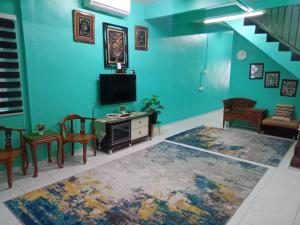 a living room with a tv and a table and chairs at NANIE DAMAI INN in Kluang +2 photos