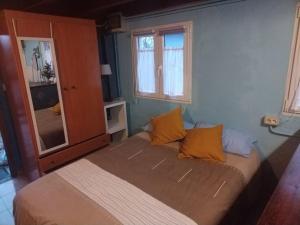 1 dormitorio con 1 cama con almohadas de color naranja en La cabañina de zuce, en Parres de Llanes