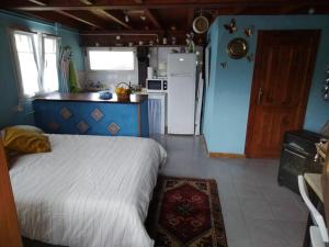 1 dormitorio con 1 cama y cocina con nevera en La cabañina de zuce, en Parres de Llanes