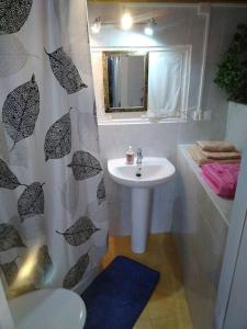 baño con lavabo y cortina de ducha con sombrillas en La cabañina de zuce, en Parres de Llanes
