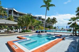 - une piscine à côté d'un complexe avec des palmiers dans l'établissement Atlantic Paradise by AvantStay Great Location w Balcony Outdoor Dining Shared Pool Hot Tub, à Key West