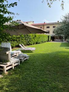 a lawn with lounge chairs and an umbrella at Appartamento La Corte Verona in Verona