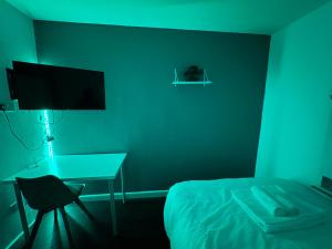 a bedroom with a bed and a desk and a monitor at Deluxe Ensuite studio in west midlands in Coventry