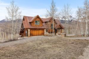 una casa de madera con un garaje en el bosque en Russell Home by AvantStay Expansive Deck Stunning Views Hot Tub, en Telluride