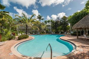 a swimming pool at a resort with palm trees at Coral Palm by AvantStay Key West Walkable Gated Community Shared Pool Month Long Stays Only in Stock Island