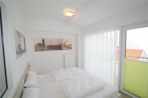 ein weißes Schlafzimmer mit einem Bett und einem Fenster in der Unterkunft Duhner Brandung, B11 in Duhnen