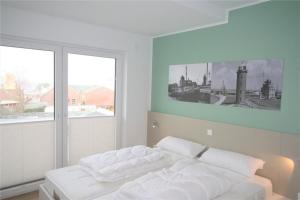 ein Schlafzimmer mit einem weißen Bett mit einem Bild an der Wand in der Unterkunft Duhner Brandung, B11 in Duhnen