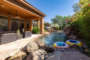 a swimming pool with two inflatable boats in front of a house at Sandflower by AvantStay Oasis w Pool Golf in Phoenix