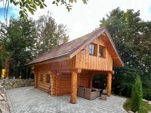 a log cabin with a roof on a patio at Zrubový Dom 1 v Panoráma Parku in Nezbudská Lúčka