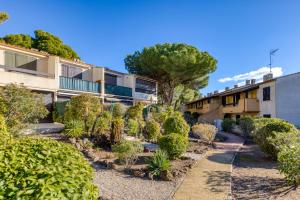 a garden in front of a building with trees and bushes at Appartement Residence Cap les Pins in Cap d'Agde