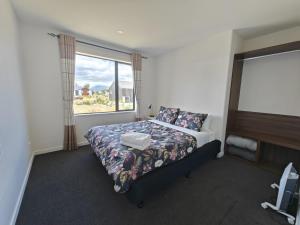 ein Schlafzimmer mit einem Bett und einem großen Fenster in der Unterkunft Hunter 3 Bedroom Apartment C in Lake Tekapo