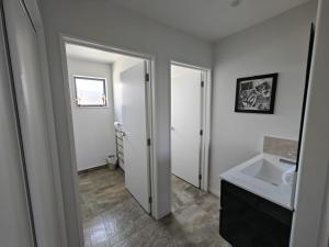 ein weißes Badezimmer mit einem Waschbecken und einem Spiegel in der Unterkunft Hunter 3 Bedroom Apartment C in Lake Tekapo