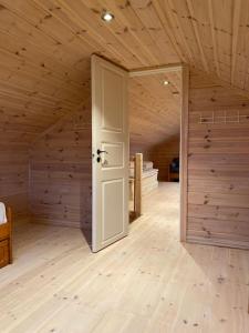 ein leeres Zimmer mit einer Tür in einem Zimmer mit Holzwänden in der Unterkunft Hytte i landlige omgivelser på Hadeland in Gran
