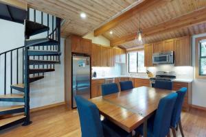 a kitchen and dining room with a wooden table and blue chairs at Sockeye by AvantStay Modern 2 BR Condo w Access to Northstar Resort Community in Kingswood Estates