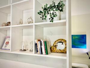 a white book shelf with books and a vase at Triumph Tower Milano Politecnico in Milan