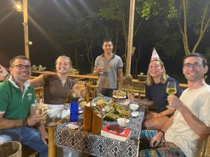 eine Gruppe von Menschen, die an einem Tisch mit Weingläsern sitzen in der Unterkunft Truong Huy Homestay in Mai Châu