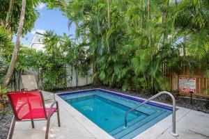 una piscina con sedia rossa e una sedia accanto ad essa di Paradise Place by AvantStay Key West Old Town Condo w Shared Pool a Key West