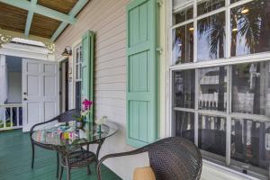 a porch with a glass table and chairs at Paradise Place by AvantStay Key West Old Town Condo w Shared Pool in Key West