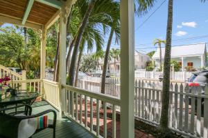 a porch with palm trees and a table at Paradise Place by AvantStay Key West Old Town Condo w Shared Pool in Key West