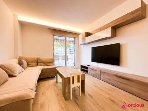 uma sala de estar com um sofá e uma televisão de ecrã plano em La Promenade em Benicàssim