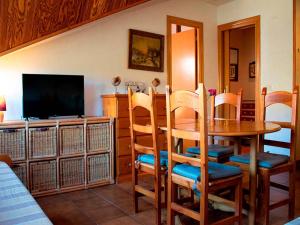 a dining room with a table and chairs and a television at Apartamentos 3000 Formigal in Formigal