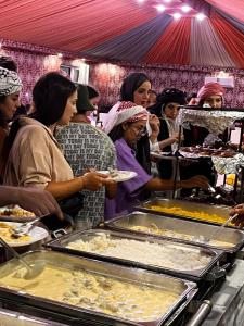 a group of people waiting for food at a buffet at wadi rum guest house camp in Aqaba