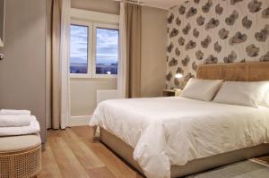 a bedroom with a white bed and a window at Apartamentos Bahia San Lorenzo in Gijón