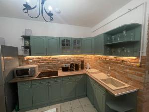 a kitchen with green cabinets and a microwave at Egri Leányka Vendégház in Eger +32 photos