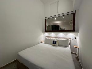 a small bedroom with a white bed with a mirror at NG Collection Piazza Castello in Sassari