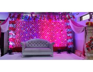 eine Bühne mit einer Couch vor einer rosa Wand in der Unterkunft Hotel Raj Inn, Agra in Agra