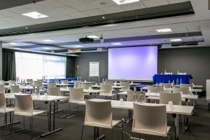 a room with tables and chairs and a projection screen at Living Place Hotel in Villanova