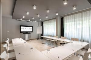 a conference room with white tables and chairs and a screen at Living Place Hotel in Villanova