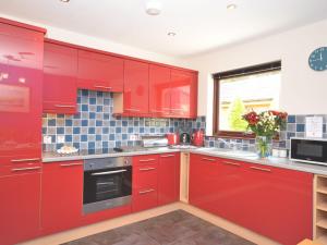 a red kitchen with red cabinets and a window at 2 Bed in Spittal 36340 in East Ord