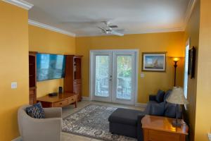 a living room with yellow walls and a couch at Coral Garden by AvantStay Great Location w Balcony Shared Pool Month Long Stays Only in Stock Island