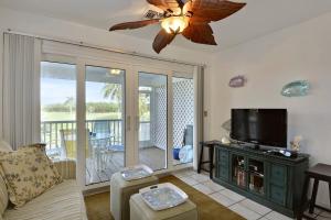 ein Wohnzimmer mit einem Sofa und einem Flachbild-TV in der Unterkunft Coral Breeze by AvantStay Close to Beach w Balcony Shared Pool Month Long Stays Only in Stock Island