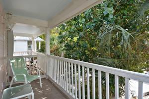 a porch with a green chair and a tree at Coral Breeze by AvantStay Close to Beach w Balcony Shared Pool Month Long Stays Only in Stock Island